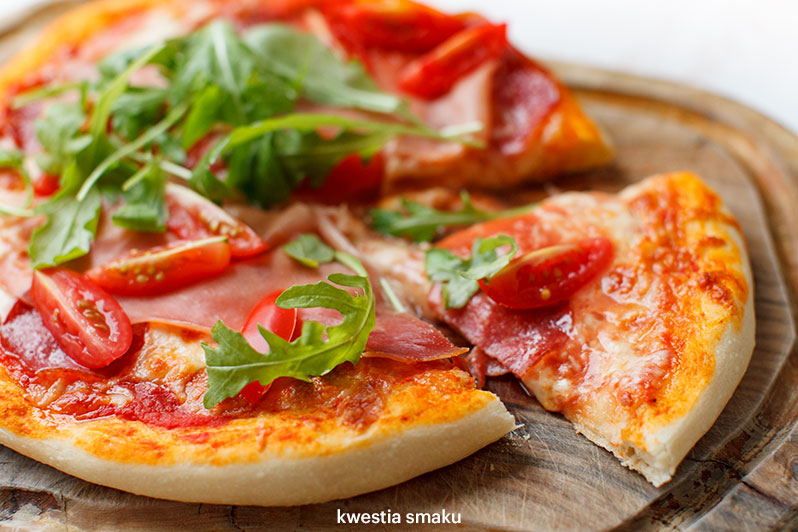 Pizza z mozzarellą, pomidorkami, suszoną szynką i rukolą